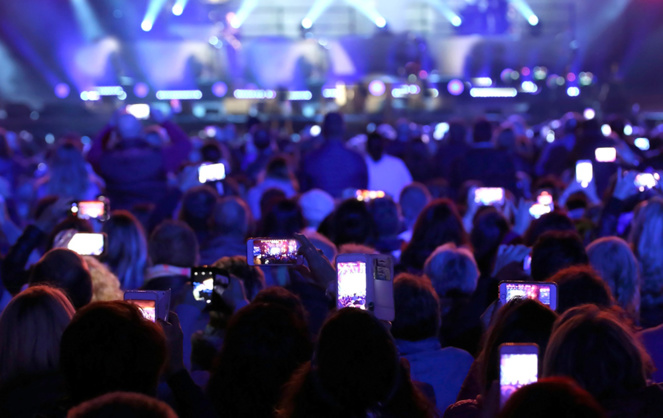 De plus en plus de spectateurs sortent leur smartphone pendant un spectacle.  (photo Adobe Stock)